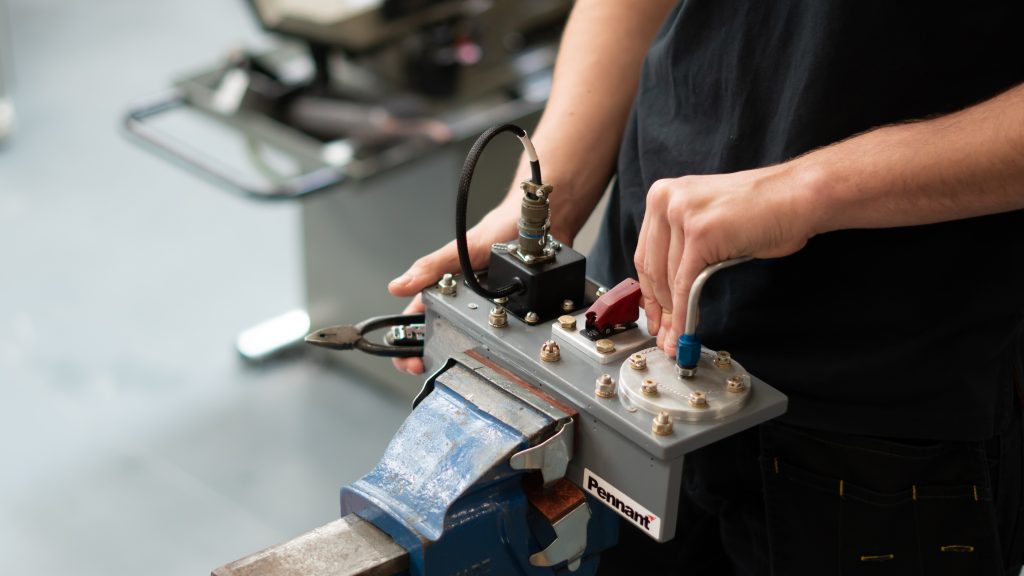 A person using a small metal training device. The device has a variety of nuts and bolts on.