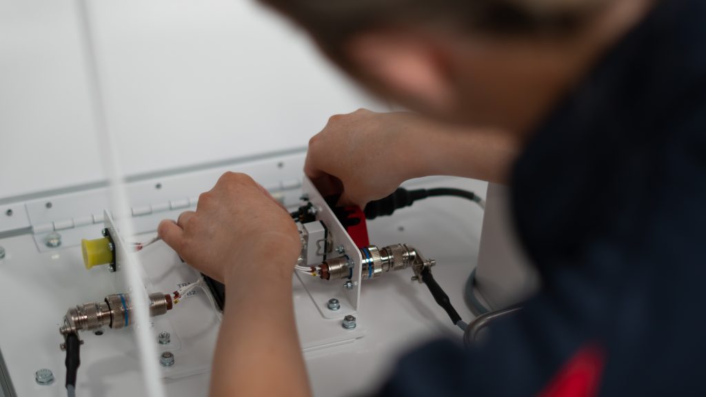 A person fixing wiring and cabling on a hardware training device