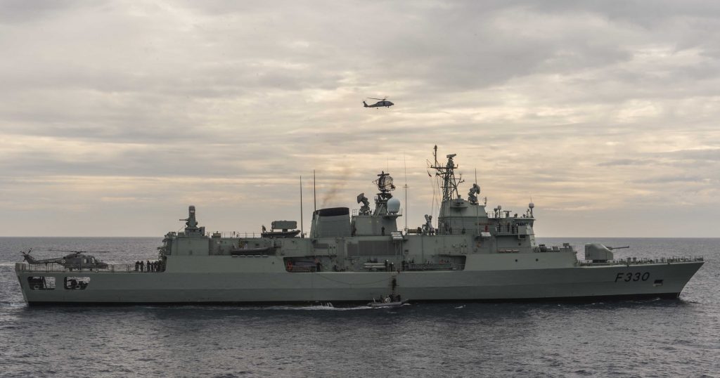 An image of a helicopter in a cloudy sky and a ship in the ocean