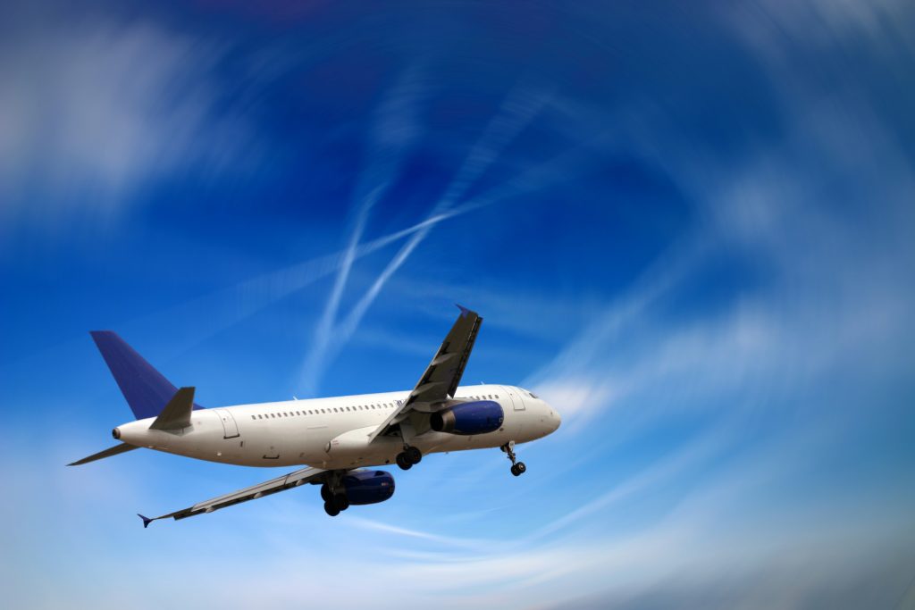 Blue sky with an aeroplane that is white and blue flying across the sky