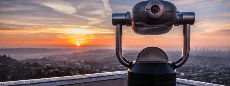 A telescope overlooking a city at dusk